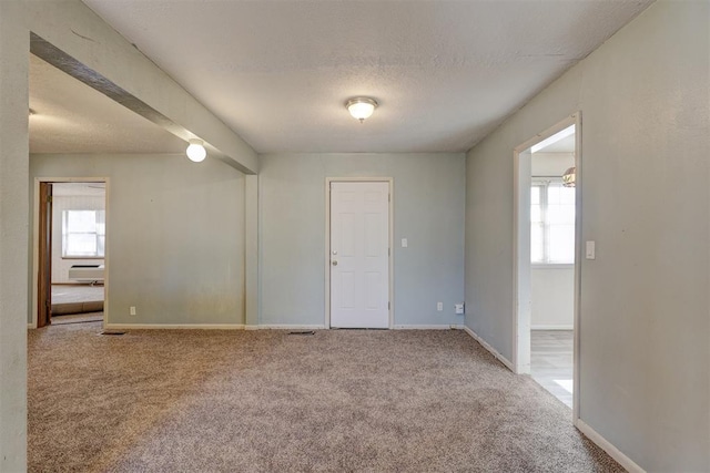 carpeted spare room featuring a textured ceiling and a wall unit AC