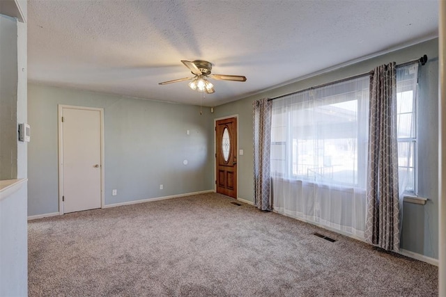 entryway with a textured ceiling, light colored carpet, and ceiling fan