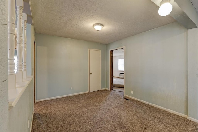 carpeted spare room featuring baseboard heating and a textured ceiling