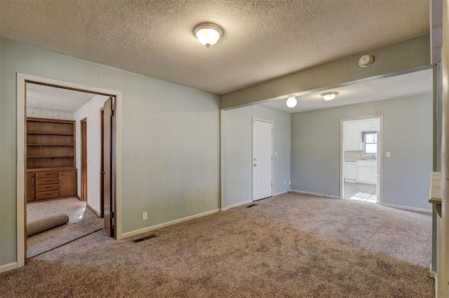 unfurnished bedroom featuring light carpet, a textured ceiling, connected bathroom, and a closet