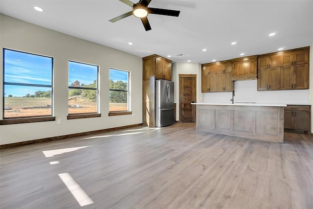 kitchen featuring a center island with sink, stainless steel refrigerator, and light hardwood / wood-style flooring