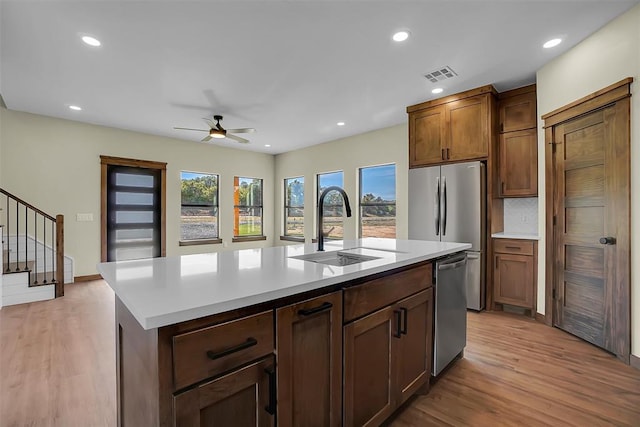 kitchen featuring sink, an island with sink, stainless steel appliances, and light hardwood / wood-style flooring