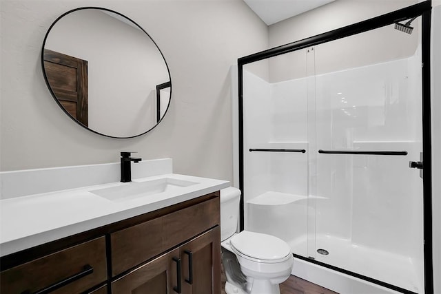 bathroom with toilet, vanity, a shower with shower door, and hardwood / wood-style flooring