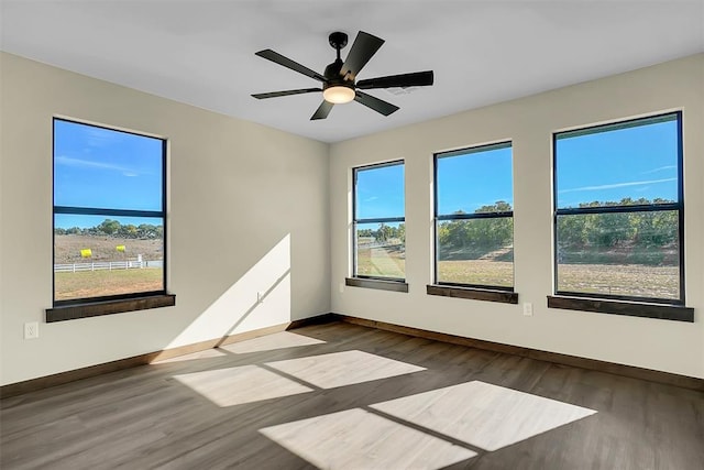 spare room with ceiling fan, dark wood-type flooring, and a healthy amount of sunlight