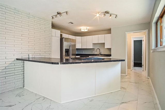 kitchen featuring white cabinetry, rail lighting, stainless steel fridge with ice dispenser, brick wall, and kitchen peninsula