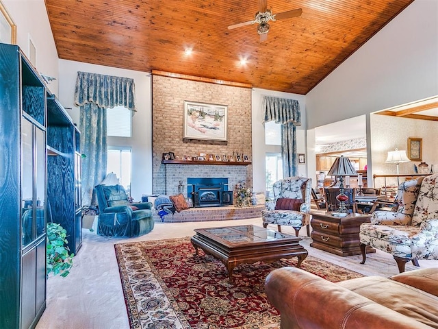 living room with ceiling fan, wooden ceiling, high vaulted ceiling, and a wood stove