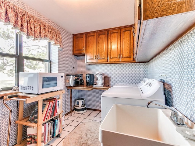 washroom with cabinets, light tile patterned floors, washing machine and dryer, and sink