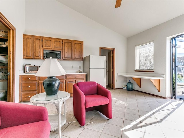 kitchen featuring ceiling fan, white fridge, light tile patterned flooring, and high vaulted ceiling