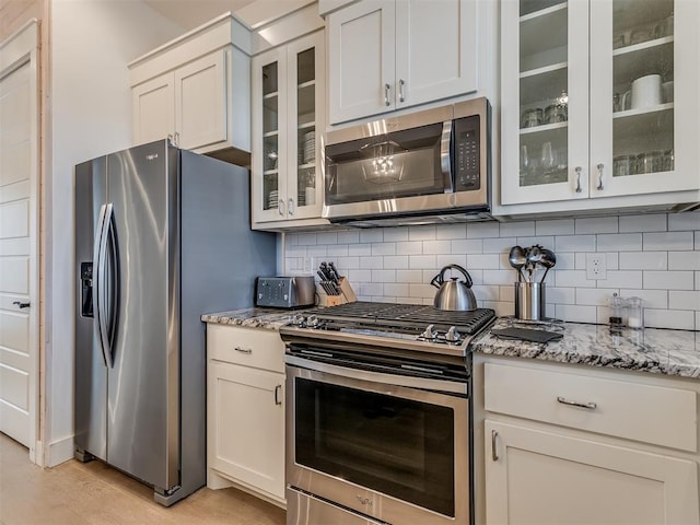 kitchen with white cabinetry, light stone counters, and stainless steel appliances