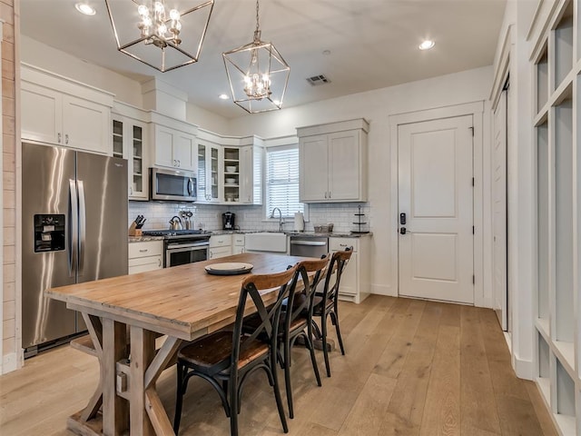 kitchen featuring pendant lighting, light hardwood / wood-style flooring, white cabinets, and stainless steel appliances