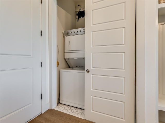 washroom with stacked washing maching and dryer and hardwood / wood-style flooring