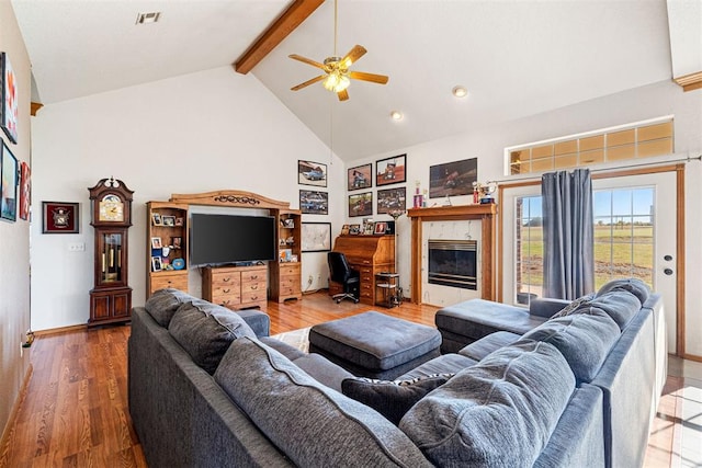 living room featuring ceiling fan, a tile fireplace, beam ceiling, high vaulted ceiling, and hardwood / wood-style floors