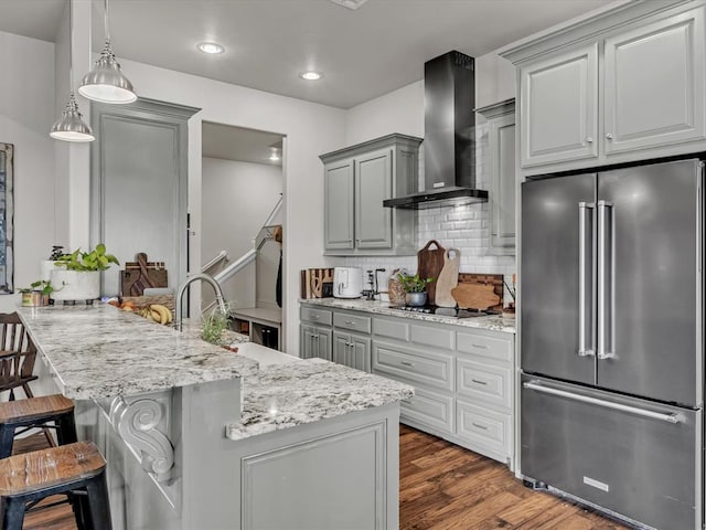 kitchen with gray cabinetry, a breakfast bar, wall chimney exhaust hood, dark hardwood / wood-style floors, and high quality fridge