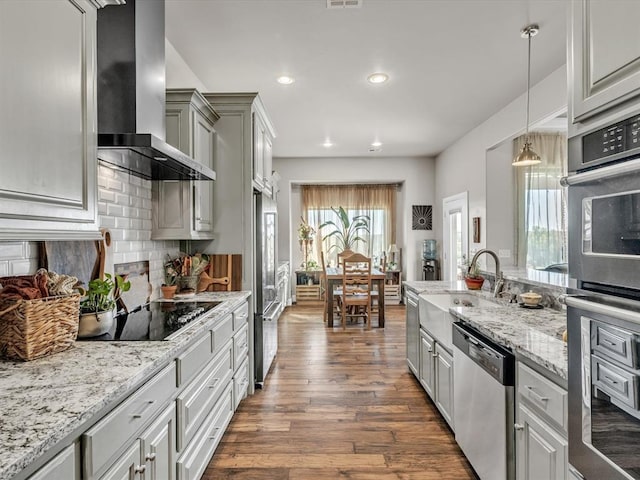 kitchen featuring backsplash, wall chimney exhaust hood, stainless steel appliances, decorative light fixtures, and dark hardwood / wood-style floors