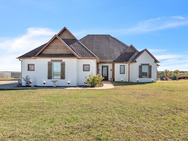 view of front of house with a shingled roof and a front lawn