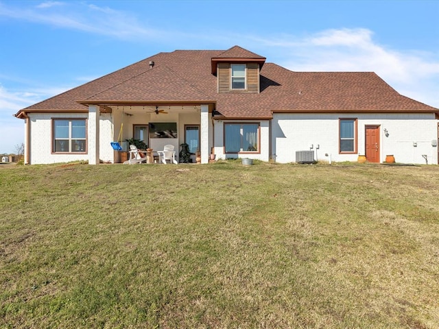 rear view of property with ceiling fan, central AC, a yard, and roof with shingles