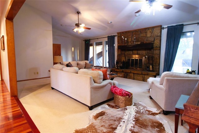 living room with a stone fireplace, light hardwood / wood-style flooring, a healthy amount of sunlight, and lofted ceiling