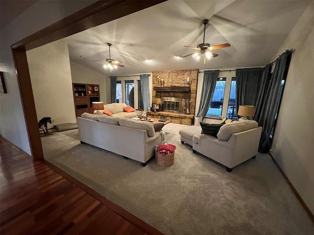 living room with ceiling fan, wood-type flooring, a stone fireplace, and vaulted ceiling