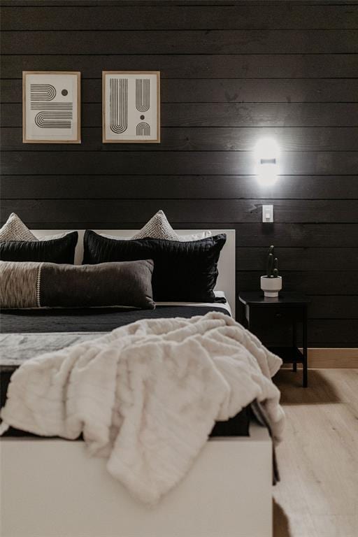 bedroom featuring hardwood / wood-style flooring and wood walls