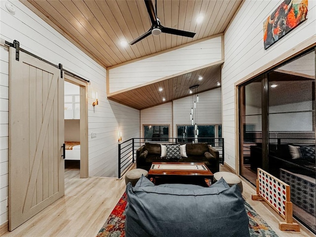 living room featuring a barn door, wooden ceiling, wooden walls, and light hardwood / wood-style flooring