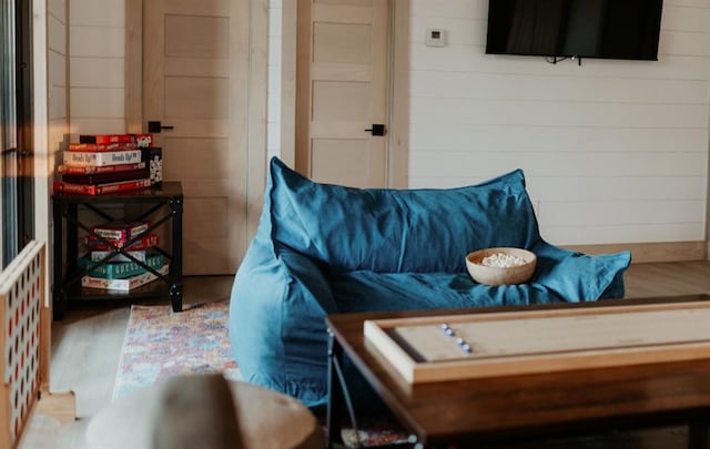 living room with hardwood / wood-style flooring and wooden walls