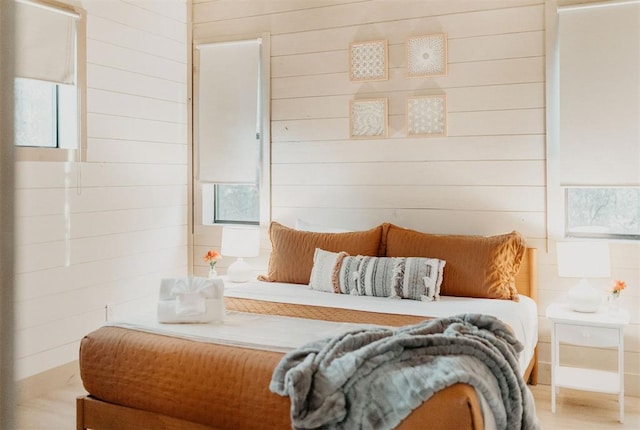 bedroom featuring light wood-type flooring and wooden walls