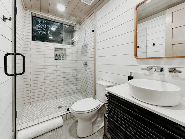 bathroom with wooden walls, vanity, a shower with shower door, and toilet