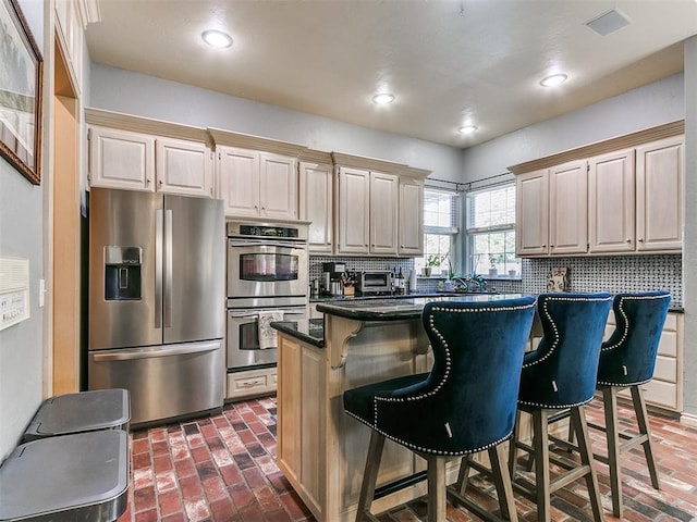 kitchen featuring decorative backsplash, a kitchen island, a breakfast bar area, and appliances with stainless steel finishes