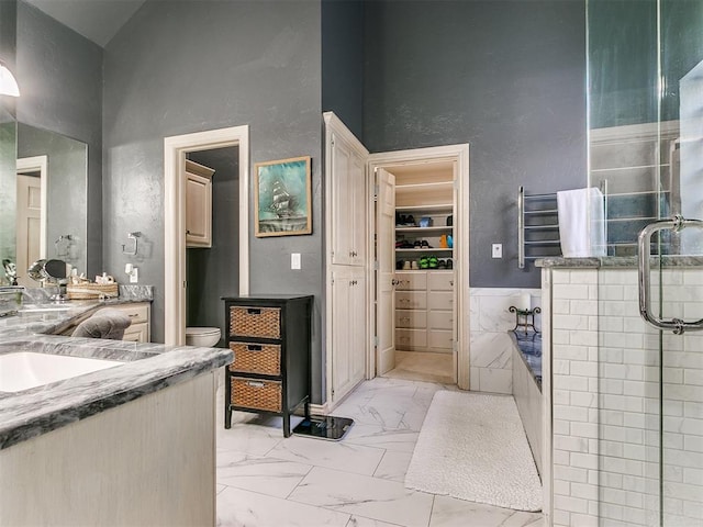 full bathroom with vanity, a high ceiling, toilet, shower with separate bathtub, and tile walls