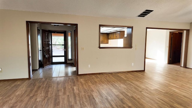 spare room featuring wood-type flooring and a textured ceiling