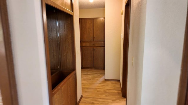 hallway with a textured ceiling and light hardwood / wood-style floors