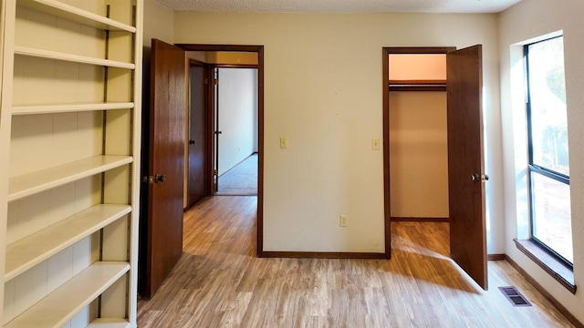 unfurnished bedroom featuring a spacious closet, light hardwood / wood-style flooring, and a closet