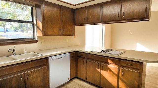 kitchen featuring sink, white dishwasher, light hardwood / wood-style floors, decorative backsplash, and kitchen peninsula