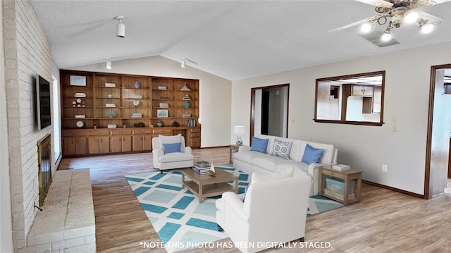 living room featuring lofted ceiling, ceiling fan, hardwood / wood-style flooring, and a textured ceiling