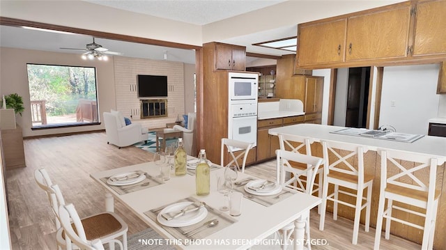 dining space featuring ceiling fan, a fireplace, and light hardwood / wood-style floors