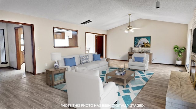 living room with hardwood / wood-style flooring, lofted ceiling, and a textured ceiling