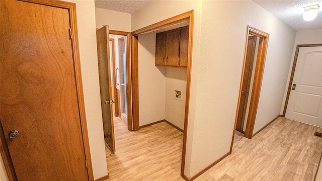 corridor featuring a textured ceiling and light hardwood / wood-style flooring