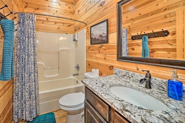 full bathroom with wooden walls, vanity, shower / tub combo, and toilet