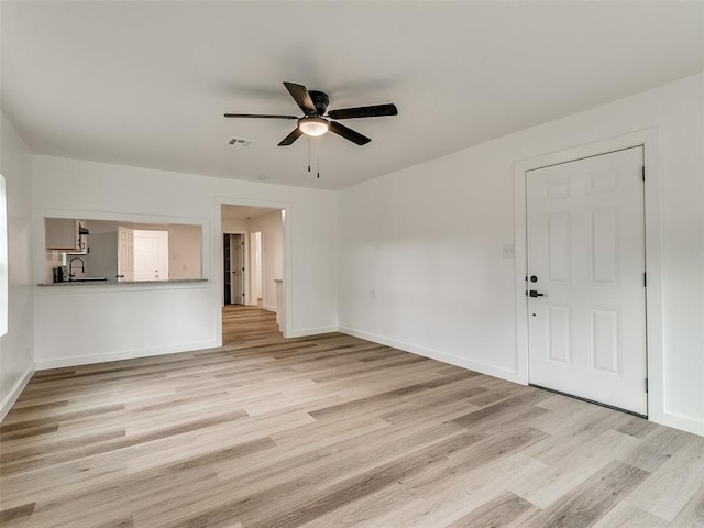 unfurnished living room with ceiling fan, sink, and light hardwood / wood-style floors