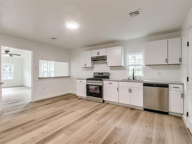 kitchen featuring ceiling fan, sink, stainless steel appliances, light hardwood / wood-style floors, and white cabinets