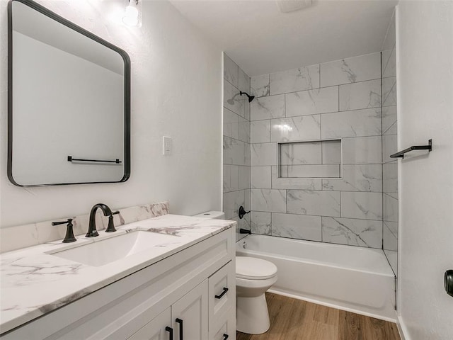 full bathroom featuring hardwood / wood-style floors, vanity, tiled shower / bath combo, and toilet