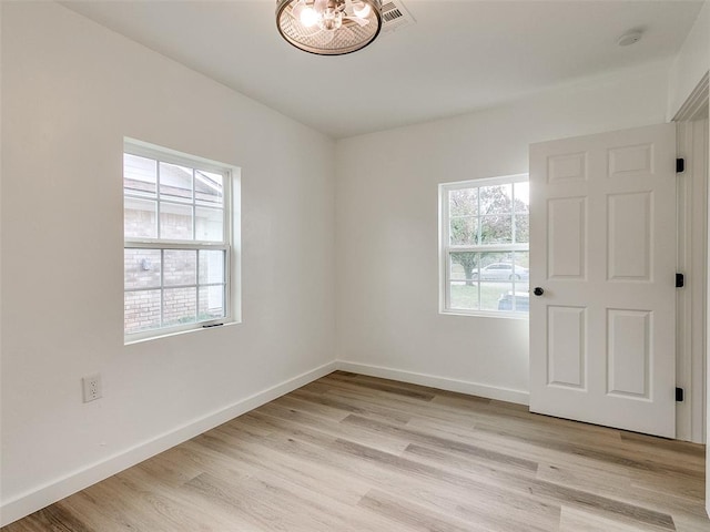 empty room with plenty of natural light and light hardwood / wood-style flooring