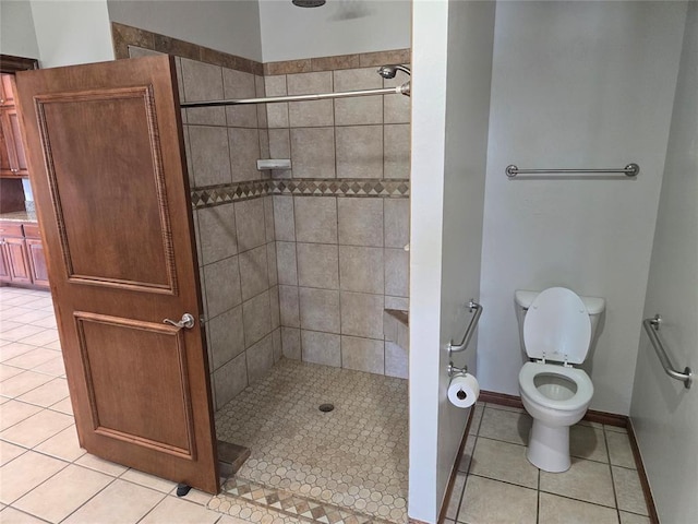 bathroom with tile patterned flooring, tiled shower, and toilet