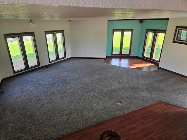 empty room with plenty of natural light, vaulted ceiling, a textured ceiling, and dark wood-type flooring