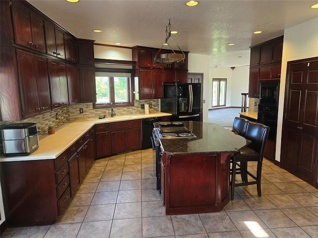 kitchen featuring a kitchen bar, tasteful backsplash, a kitchen island, and black appliances