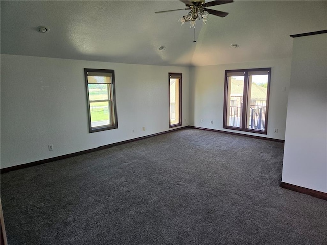 spare room featuring ceiling fan, dark carpet, and lofted ceiling