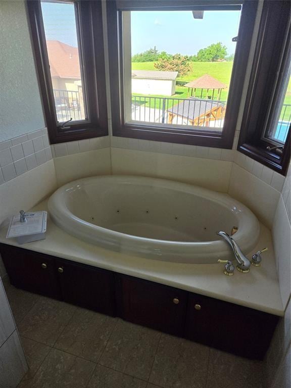 bathroom with a tub to relax in and tile patterned floors