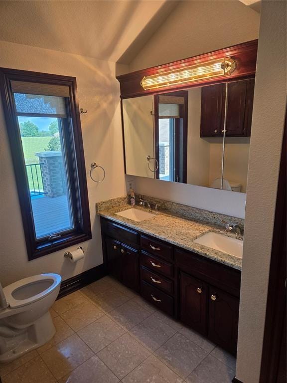 bathroom with toilet, tile patterned floors, vanity, and vaulted ceiling