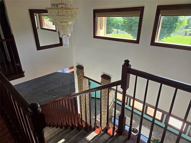 staircase with an inviting chandelier and plenty of natural light