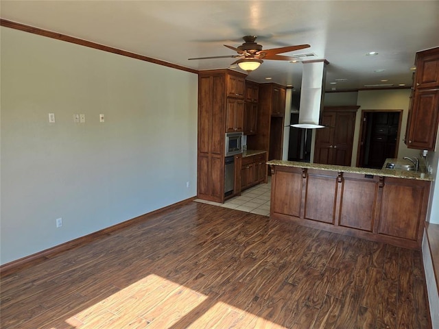 kitchen featuring kitchen peninsula, stainless steel microwave, light hardwood / wood-style floors, and range hood